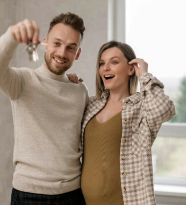 A young couple holding up keys to a new house